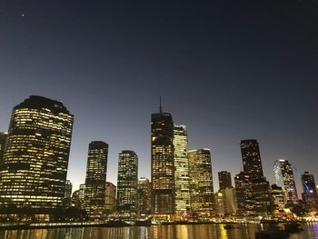 Illuminated buildings in city against sky at night