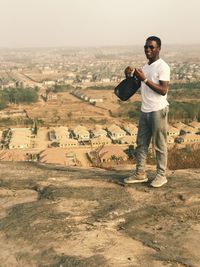 Full length portrait of young man standing on landscape