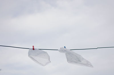 Close-up of plastics hanging on clothesline against sky