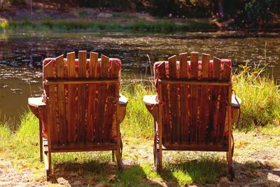 Deck chairs on field by lake