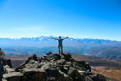 Full length man standing on mountain against blue sky