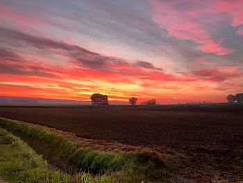 Scenic view of field against dramatic sky during sunset