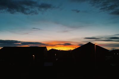 Silhouette houses against sky during sunset