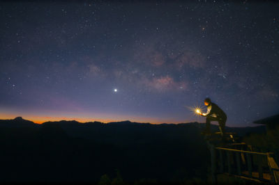 Low angle view of man standing against star field