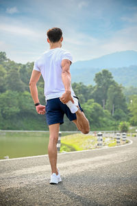 Side view of woman walking on road against sky