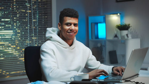 Portrait of young man using laptop while sitting on table