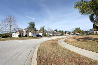 Road by buildings in city against sky