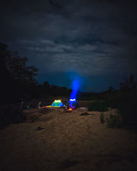 Illuminated lighting equipment on land against sky at night