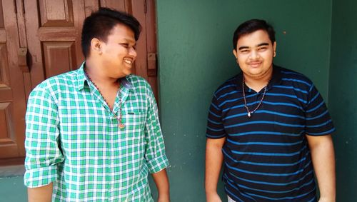 Close-up of happy friends standing against window