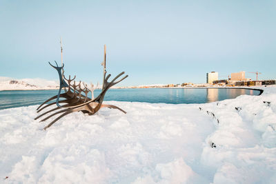 Snow on shore against sky during winter