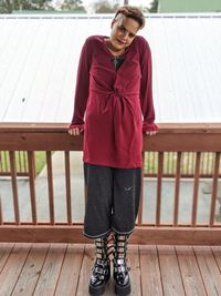 Portrait of woman standing against wooden railing