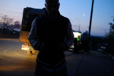 Rear view of man standing on road at sunset