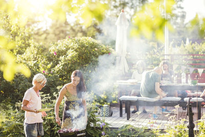 Mature women barbecuing in back yard on sunny day