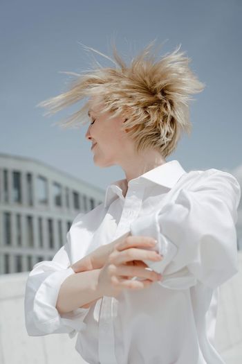 MIDSECTION OF WOMAN WITH ARMS RAISED STANDING OUTDOORS