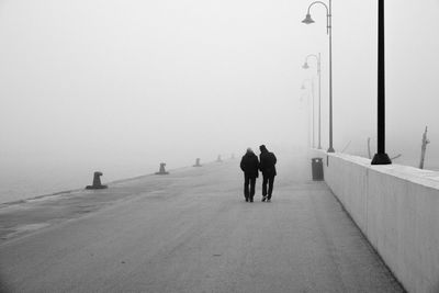 Rear view of people walking on road against sky