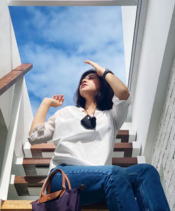 Young woman sitting on seat against sky