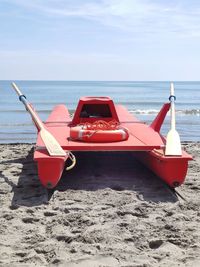 Red boat on beach against sky