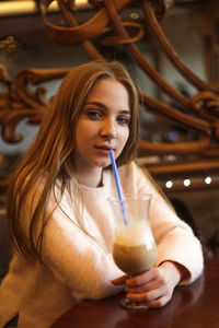 Beautiful young woman in a cafe with a glass of coffee with milk