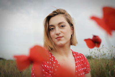 Portrait of smiling young woman against red flowering plants