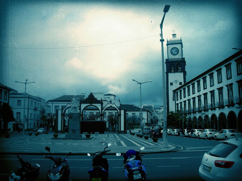 building exterior, architecture, built structure, car, street, transportation, sky, land vehicle, street light, city, mode of transport, city street, city life, road, incidental people, transfer print, cloud - sky, men, travel