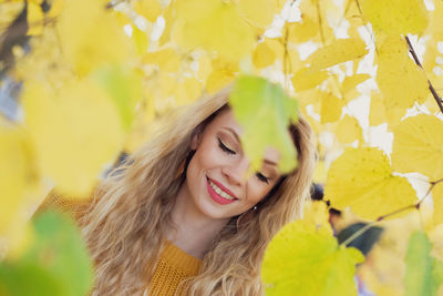 Portrait of smiling young woman with yellow leaves