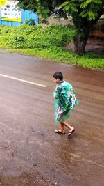 Rear view of boy walking on road