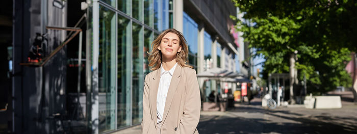 Portrait of young woman standing in city