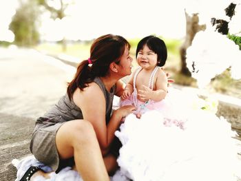 Woman with her cute daughter sitting outdoors