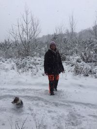 Man with dog walking on snow field