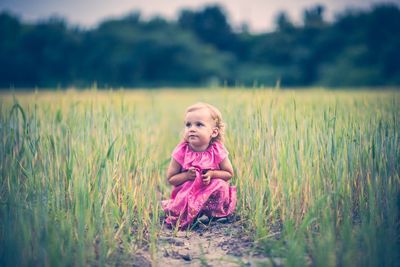 Portrait of young girl sitting on grassy field