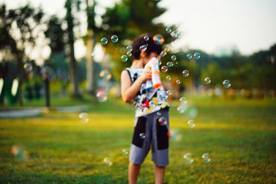 Boy standing with bubbles in mid-air at park