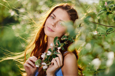 Portrait of young woman with eyes closed against plants