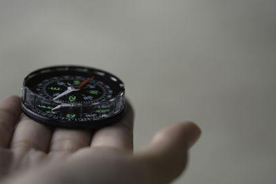 Close-up of hand holding navigational compass against wall