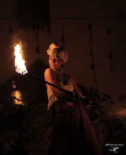 Midsection of woman holding burning fire at night