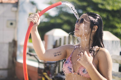 Woman in bikini having shower at yard