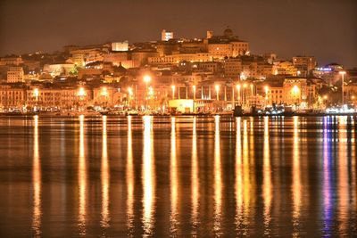 Illuminated town with reflection in sea at cagliari
