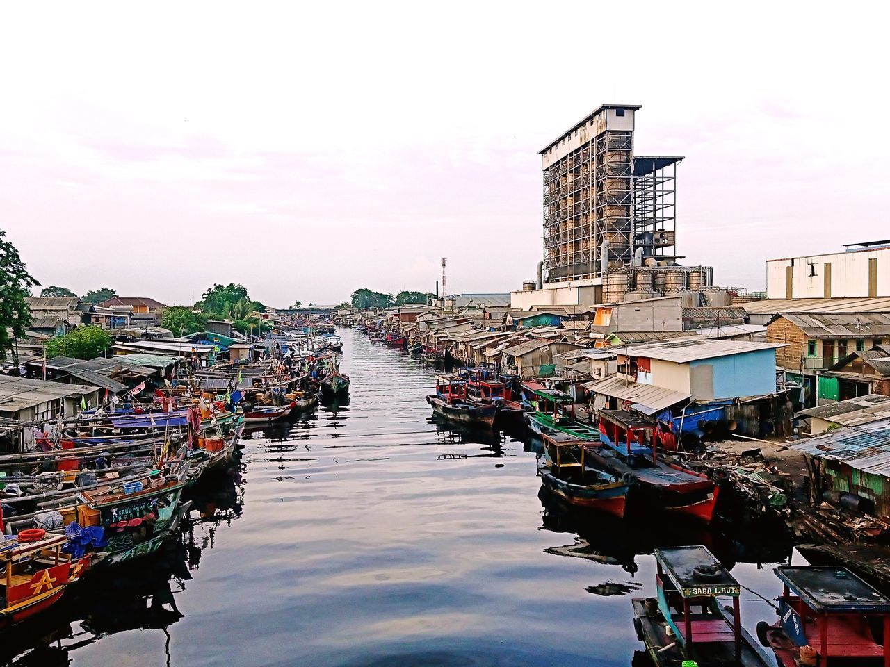 BOATS MOORED AT HARBOR BY BUILDINGS IN CITY