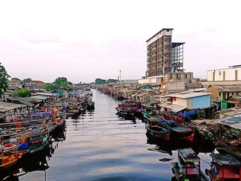 Boats moored at harbor against buildings in city