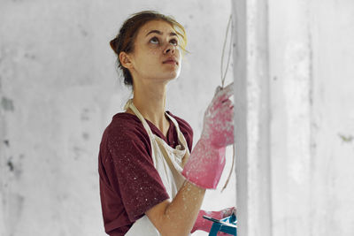 Portrait of young woman standing against wall