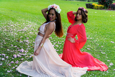 Portrait of young women kneeling on grassy field at public park