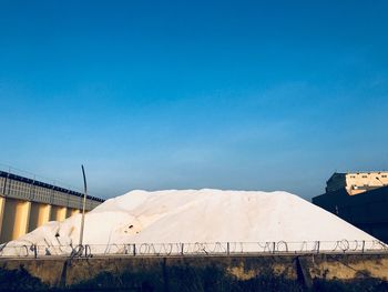 Houses on snow covered land against blue sky