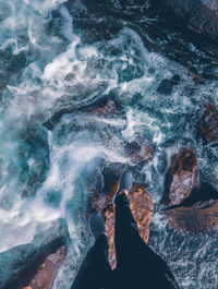 Low section of person standing on rock by sea