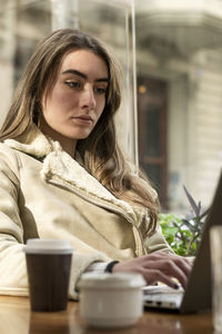 Young woman wearing warm clothing using laptop