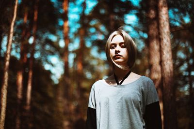 Portrait of woman standing by tree in forest