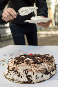 Midsection of person holding ice cream on table