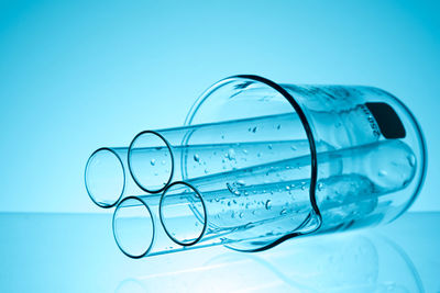 Close-up of wet laboratory glassware on table against blue background