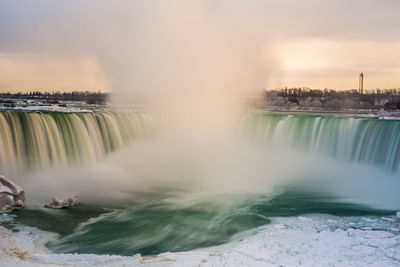 Scenic view of waterfall against sky