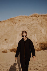 Portrait of young man wearing sunglasses standing against clear sky