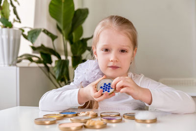 A girl student sits at a desk in the classroom and collects figures / puzzles / small toys 