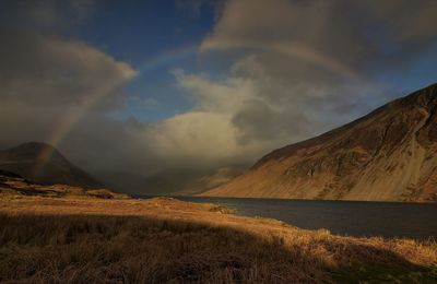 Scenic view of landscape against sky with rainbow during sunset